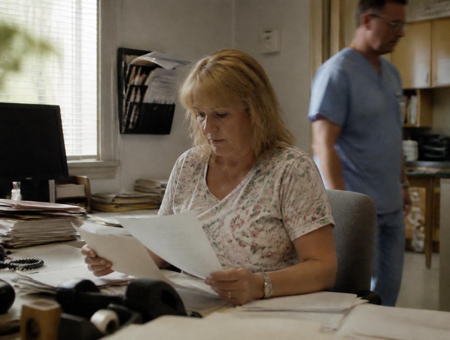 Practice administrator and physician reviewing operations at the front desk of a medical office